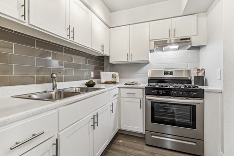 a white kitchen with stainless steel appliances and white cabinets