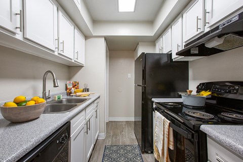 a kitchen with white cabinets and black appliances and a sink