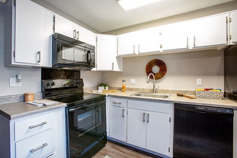 a kitchen with white cabinets and black appliances and a sink