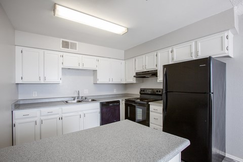 a kitchen with white cabinets and a black refrigerator