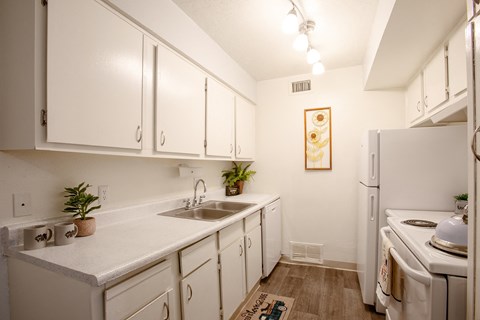 A kitchen with white cabinets and a white fridge.