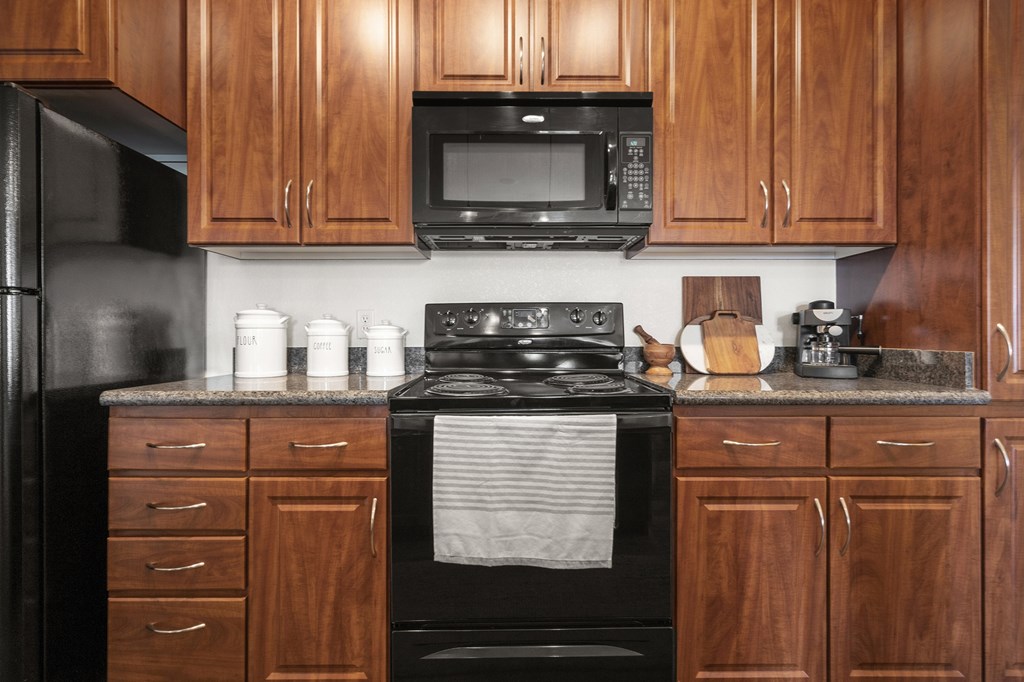 A kitchen with wooden cabinets and a black stove top oven.