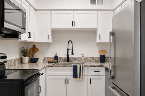 A kitchen with white cabinets and a black stove top oven.