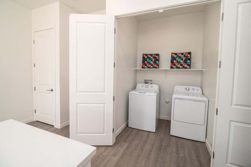 a white laundry room with a washer and dryer and shelves