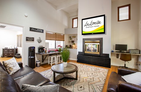A living room with a fireplace and a sign that says "LaLomita Apartment Homes".