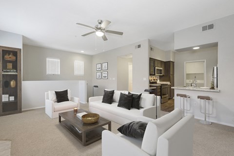 a living room with white furniture and a ceiling fan