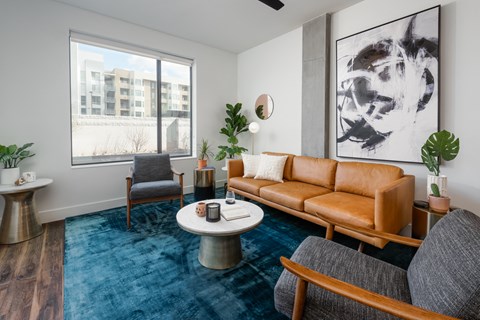 a living room with a blue rug and leather couch
