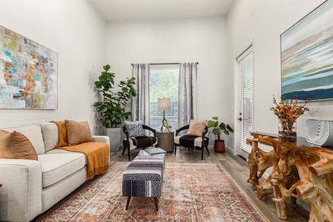 A living room with a white couch, a wooden coffee table, and a large painting on the wall.