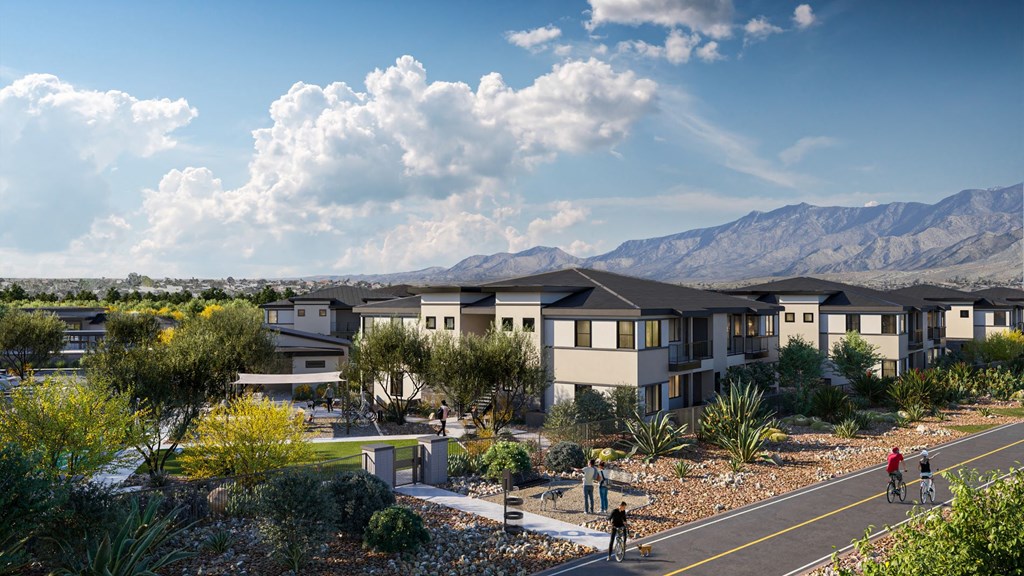 an aerial view of a row of houses with people biking on a road and mountains in the