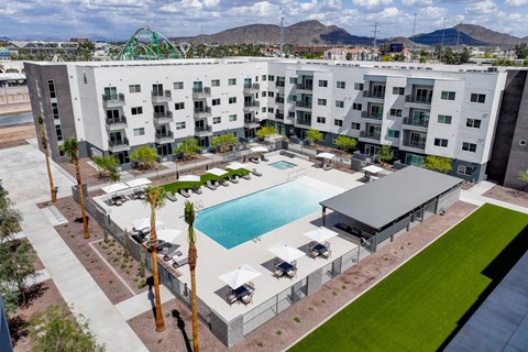 A large white apartment complex with a pool in the middle.