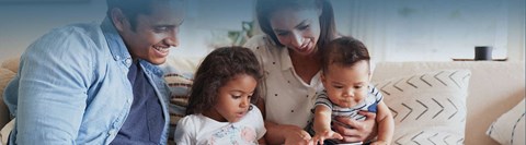a family sitting on a couch looking at a cell phone