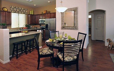 A kitchen with a table and chairs and a dog.