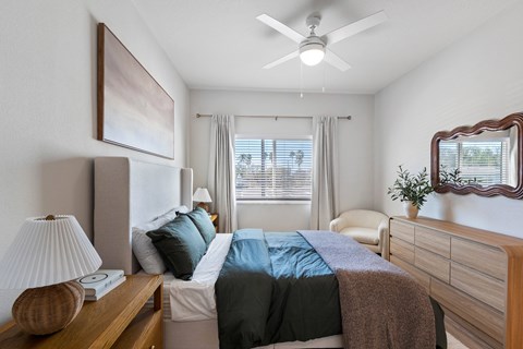 A bedroom with a bed, a nightstand with a lamp, and a window with curtains.
