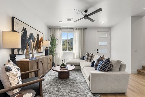 A living room with a grey sofa, a wooden cabinet, a coffee table, and a painting on the wall.