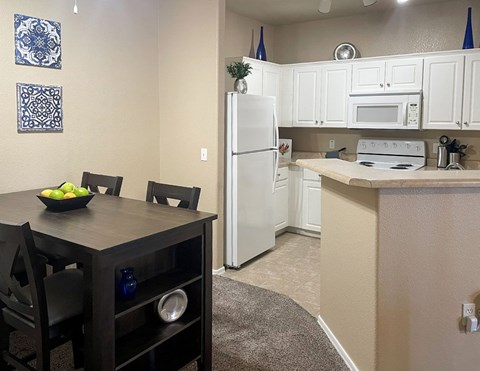A kitchen with a table and chairs and a bowl of fruit on it.