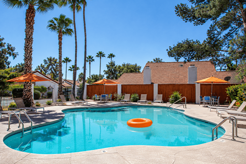A pool with a blue tinted water and a floating orange ring in the middle.