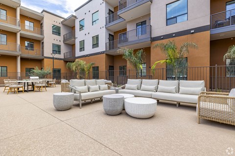 A patio area with white furniture and a table surrounded by apartment buildings.