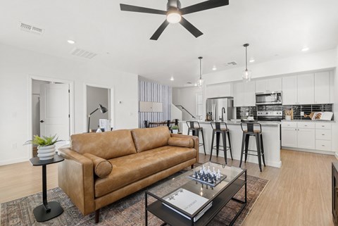 A living room with a brown leather couch and a ceiling fan.