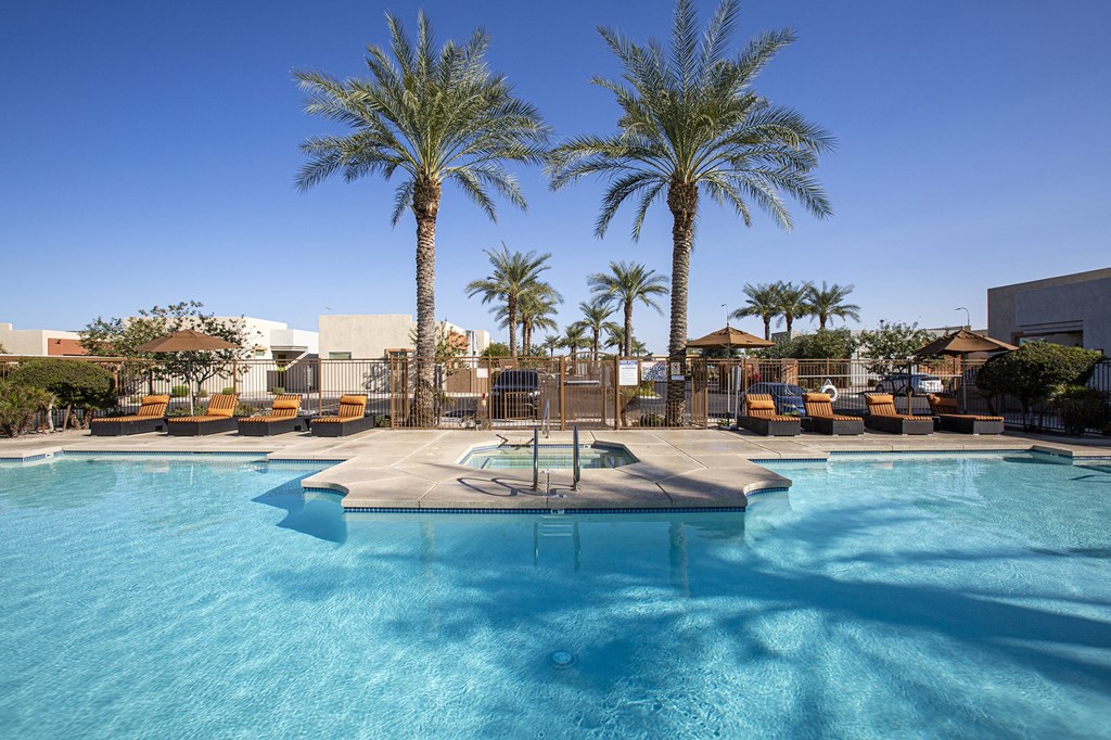 a resort style pool with lounge chairs and palm trees
