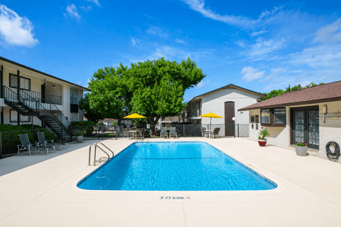 A swimming pool surrounded by a patio with chairs and umbrellas.