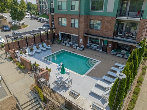 A pool surrounded by chairs and a building in the background.