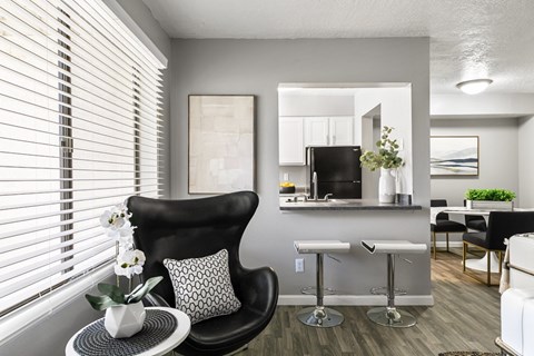 A black chair sits in front of a table with a vase of flowers on it.