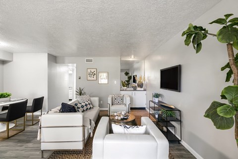 A living room with white furniture and a flat screen TV mounted on the wall.