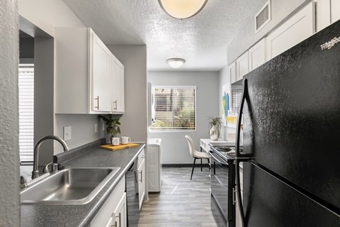A black refrigerator is in the foreground of a modern kitchen.