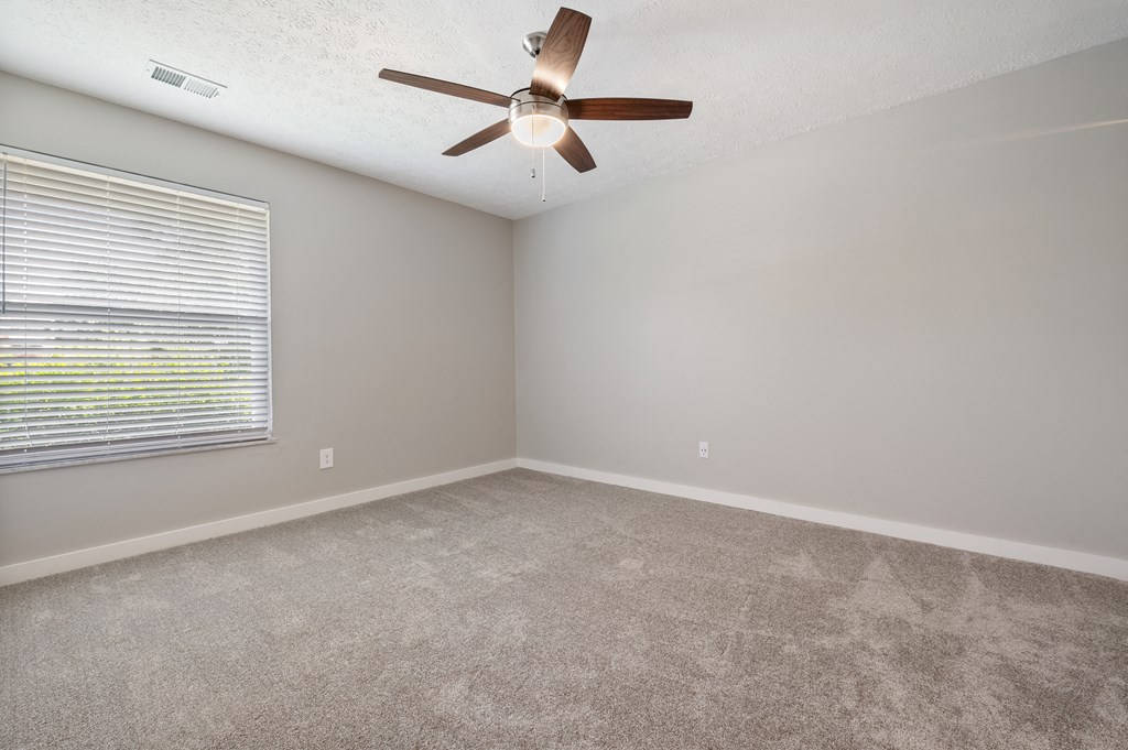 A room with a ceiling fan and carpeted floor.