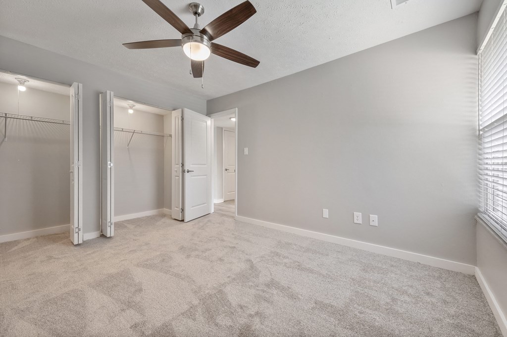 A room with a ceiling fan and carpeted floor.