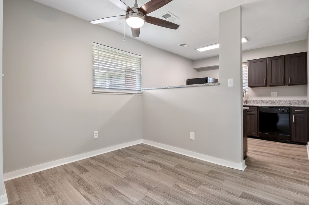 A room with a ceiling fan and wooden flooring.