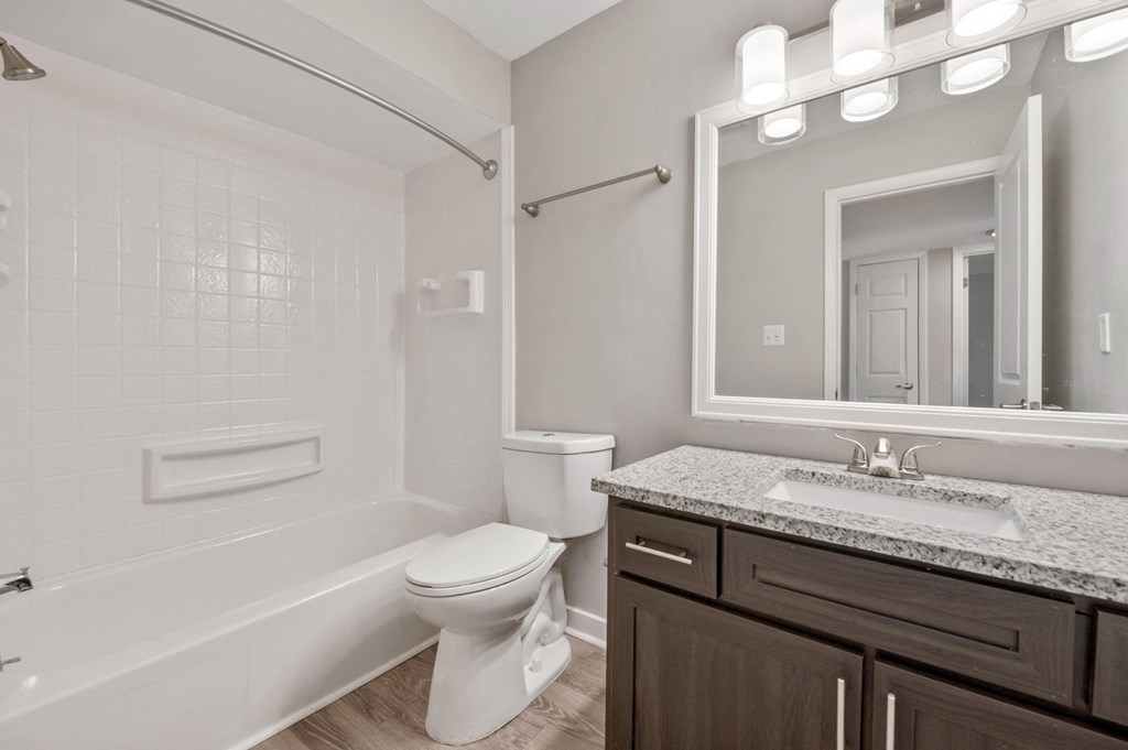 A white toilet sits in a bathroom next to a bathtub.