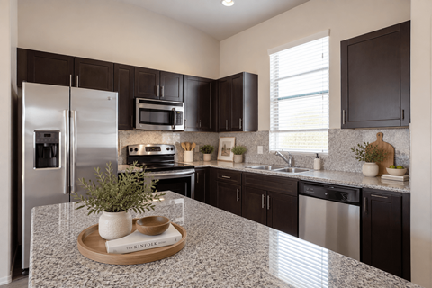 A kitchen with a granite countertop and stainless steel appliances.