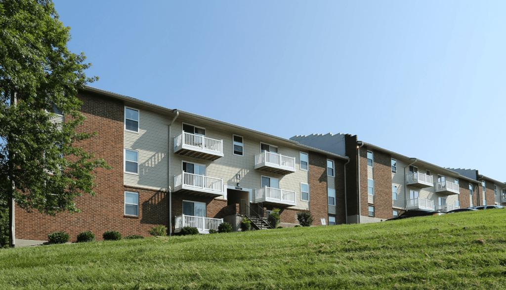 Apartment building with balconies and a green lawn in front.