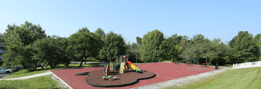 A playground with a red surface and a yellow slide.