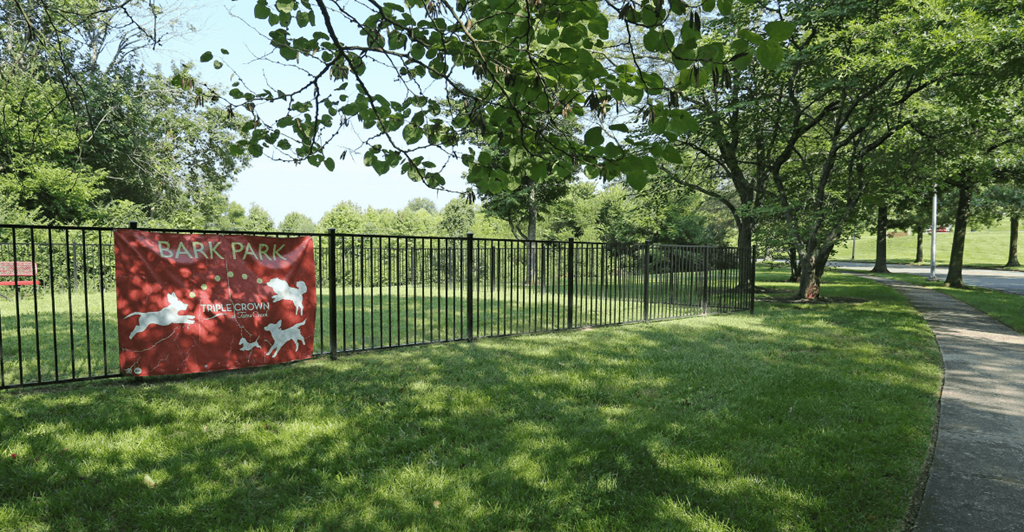 A red sign with white writing is on a black fence.