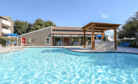 A swimming pool in front of a building with a red door.