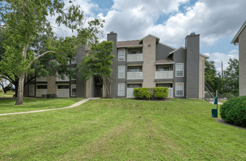 A large apartment complex with a grassy area in front.