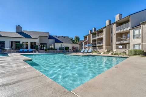 A large swimming pool in front of a building with a clear blue sky.