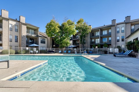 A large swimming pool in front of apartment buildings.