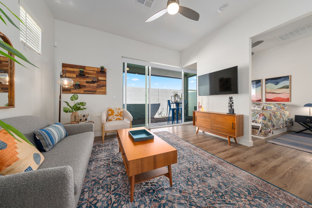 A living room with a grey couch, a wooden coffee table, and a flat screen TV mounted on the wall.