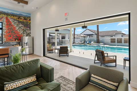 A living room with a green couch and a view of a pool through a glass door.