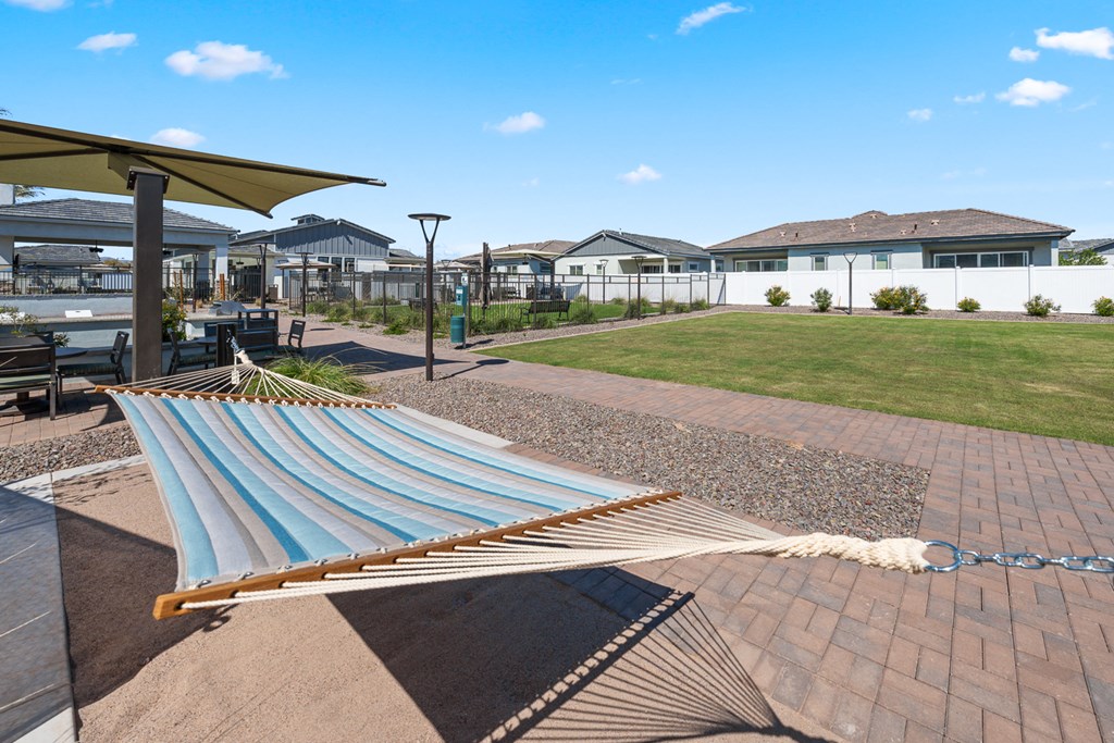 A hammock is strung between two poles in a backyard.