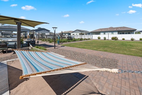 A hammock is strung between two poles in a backyard.
