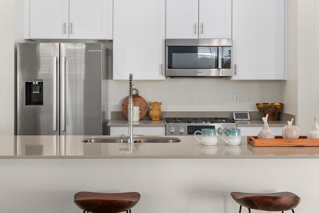 A modern kitchen with a stainless steel refrigerator and a microwave above the stove.
