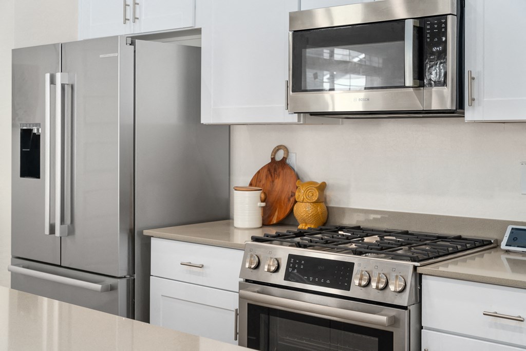 A modern kitchen with a stainless steel refrigerator, microwave, and oven.
