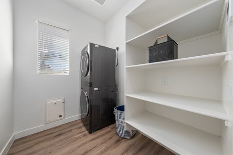 A black refrigerator sits in a kitchen next to a window.