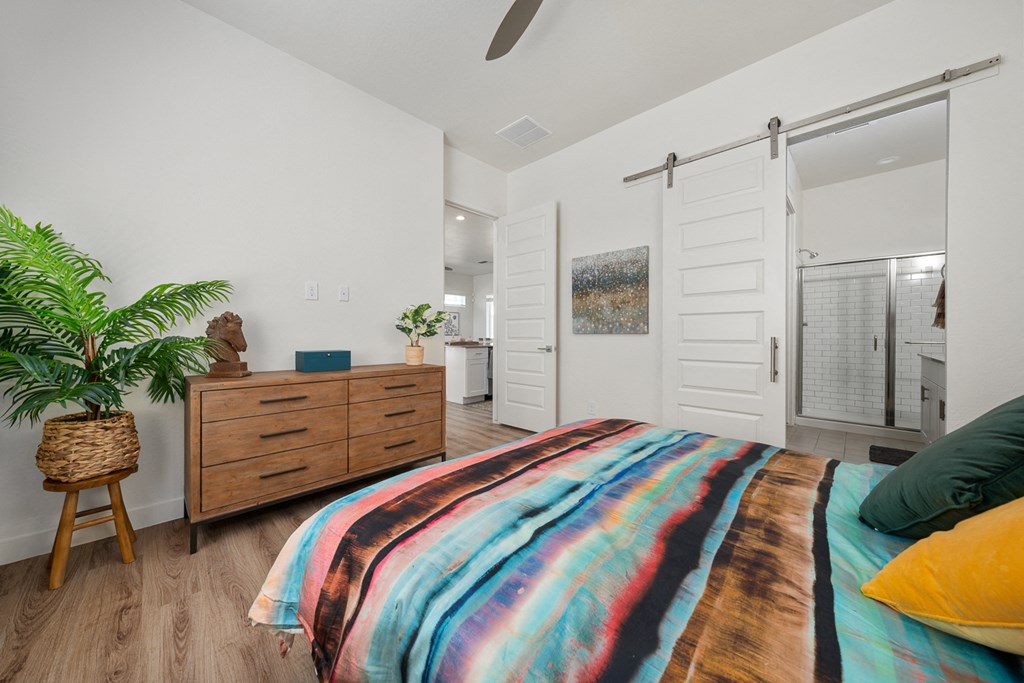 A bedroom with a bed, a dresser, and a plant.