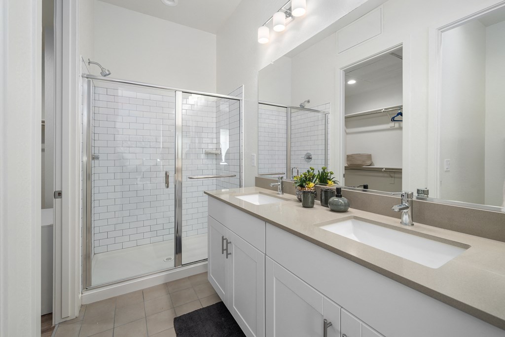 A bathroom with a walk-in shower and double sinks.