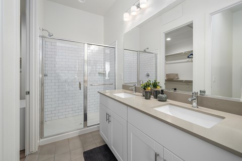 A bathroom with a walk-in shower and double sinks.